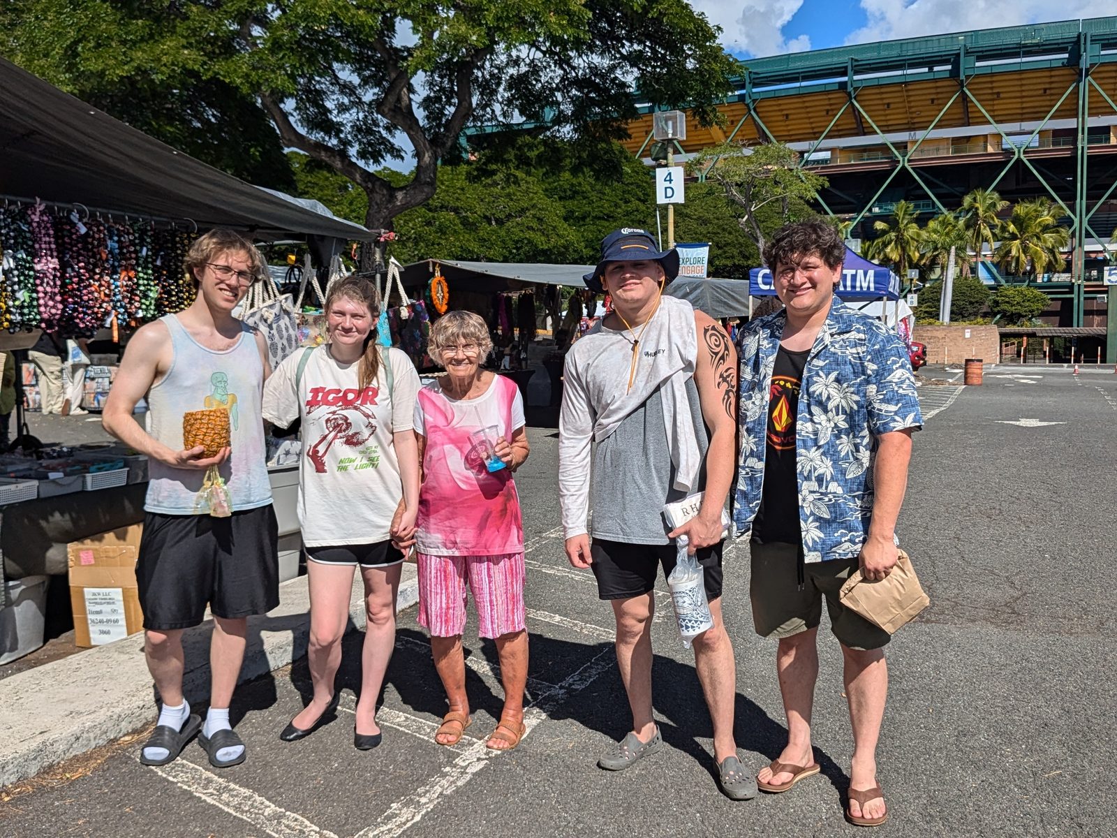 Family in the Aloha Stadium Swap Meet lot with the stadium behind, November 2024
