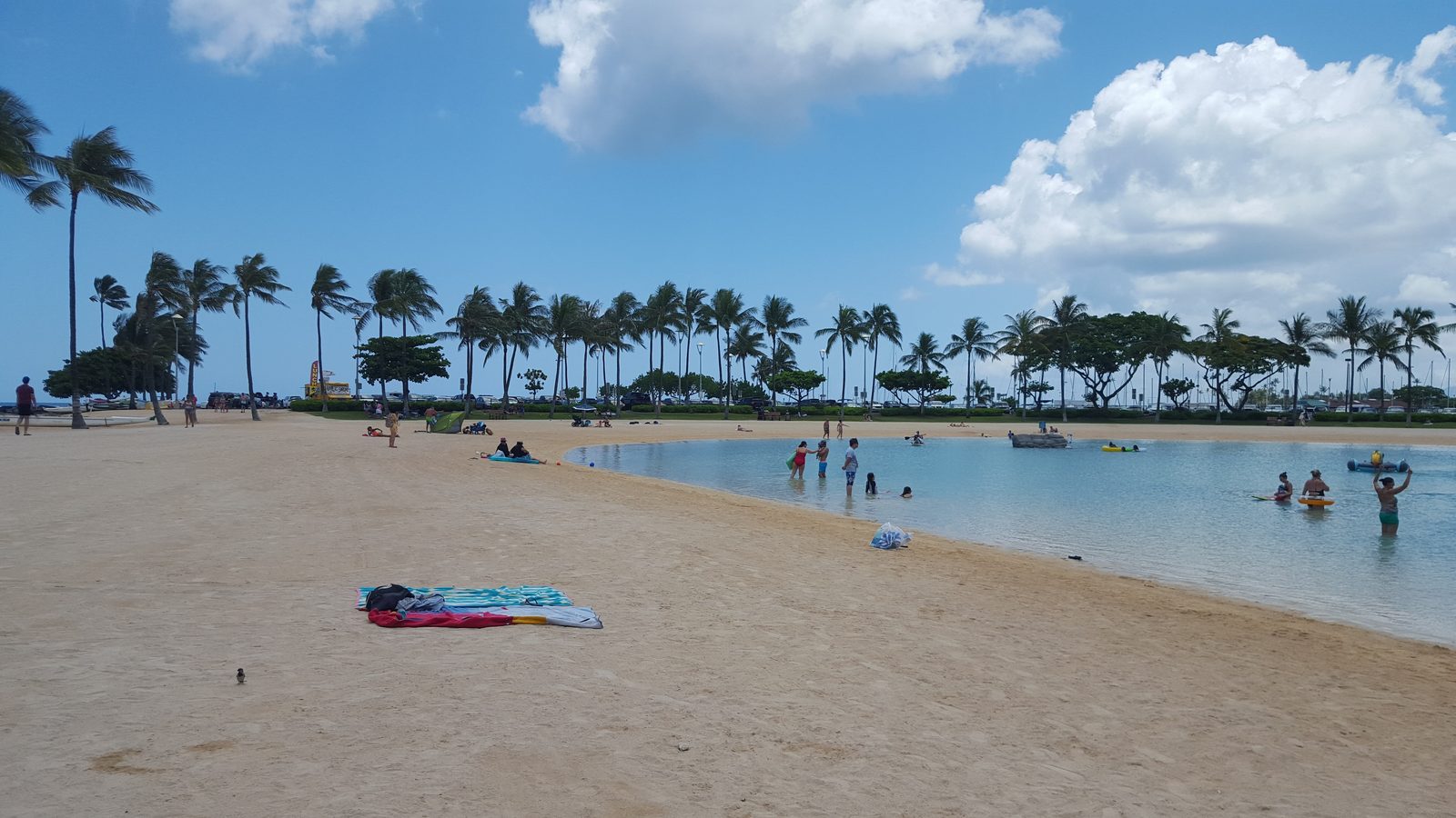 The wide beach beside Duke Kahanamoku Lagoon with palms and Waikiki beyond
