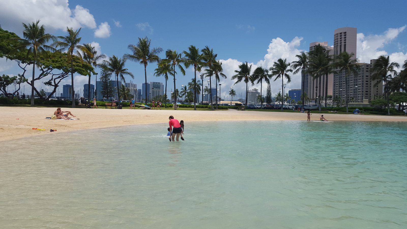 Families at the shallow sandy edge of Duke Kahanamoku Lagoon