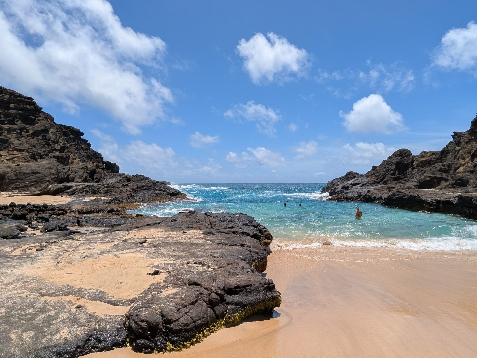 The lava shelf and clear turquoise water inside Halona Cove, with swimmers beyond the rocks