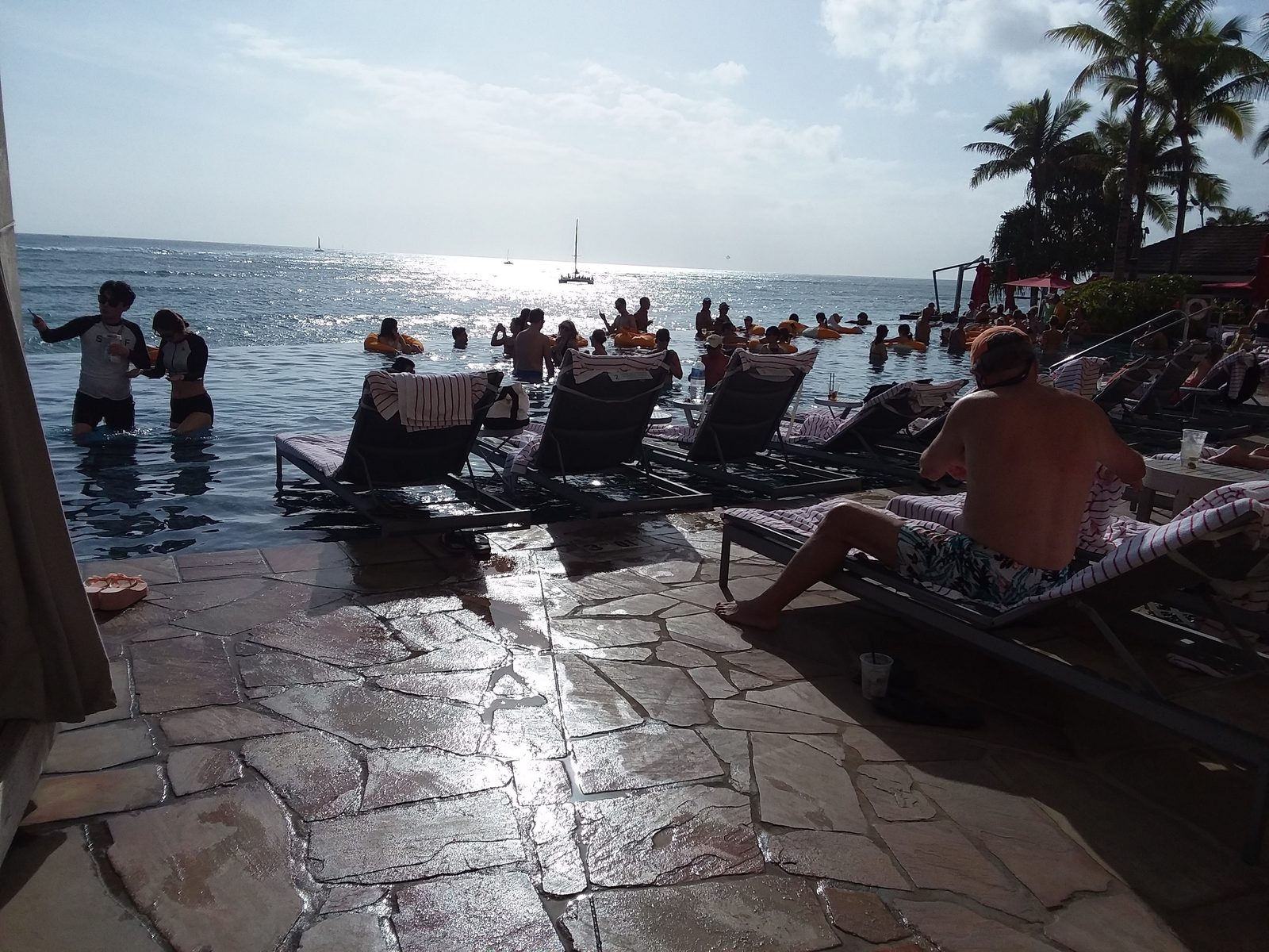 The Sheraton Waikiki infinity pool deck with loungers in the water and the ocean beyond
