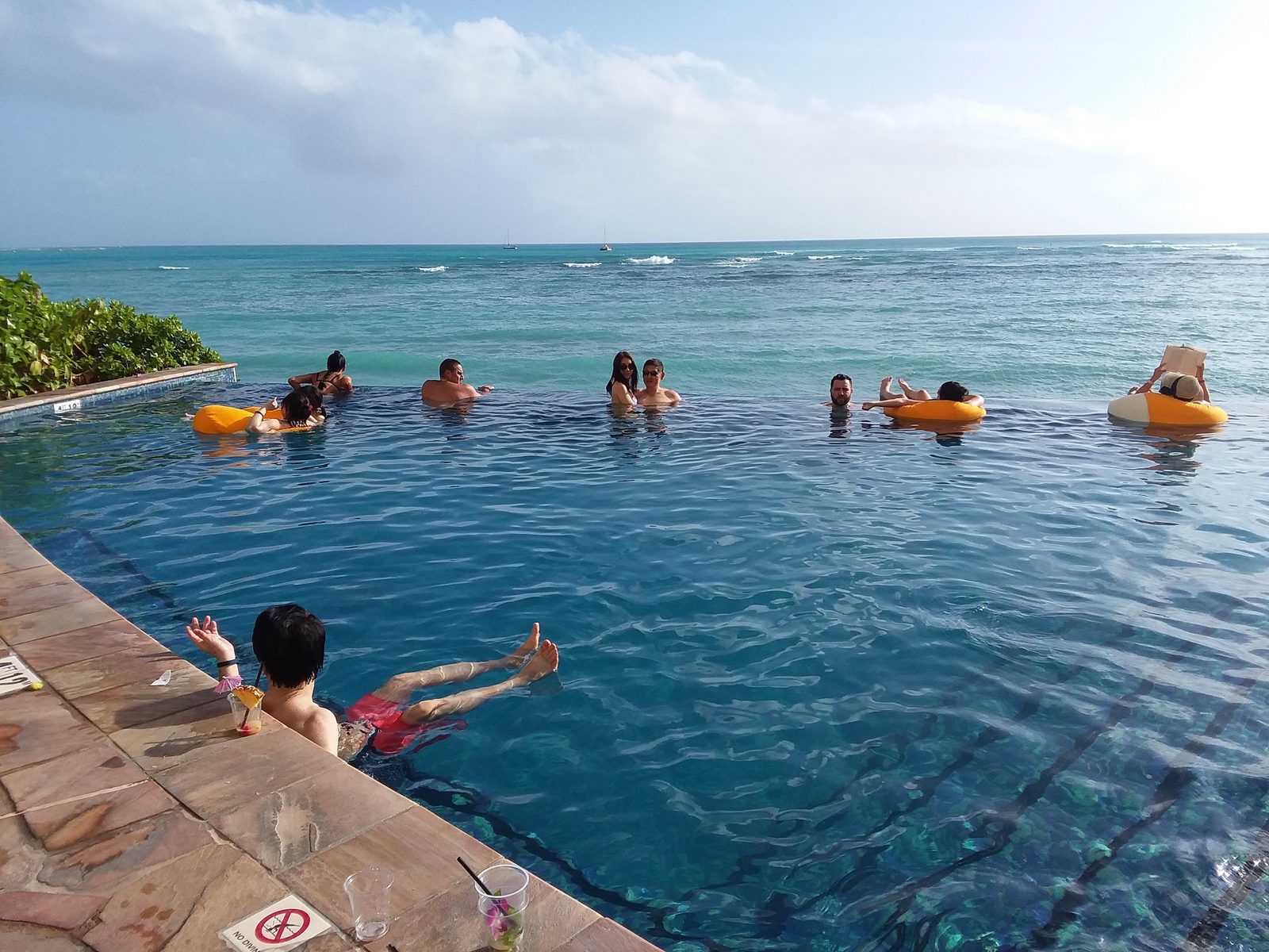 Swimmers along the infinity edge of the Sheraton Waikiki pool, the Pacific behind them