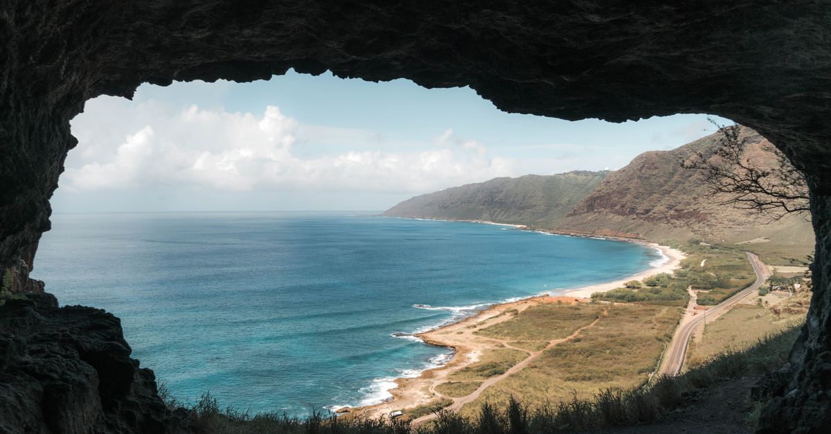 Coastal landscape viewed from inside a cave, ocean waves beyond