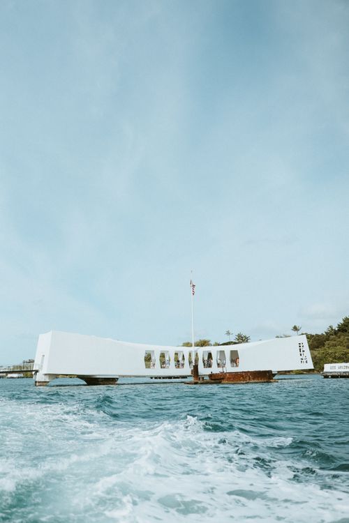 Classic view of the USS Arizona Memorial from the water with a boat wake in the foreground