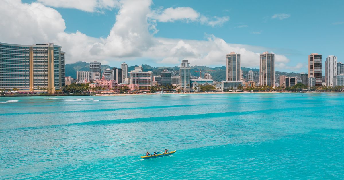 Outrigger canoe with paddlers gliding across turquoise water