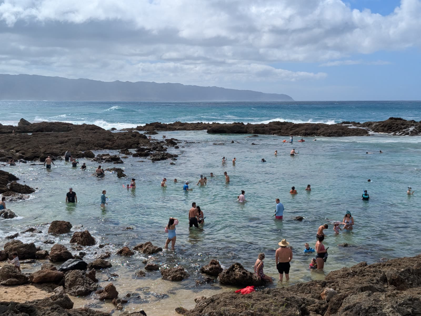 Snorkelers exploring the tide pools at Shark’s Cove with Ka’ena Point in the distance, November 2025