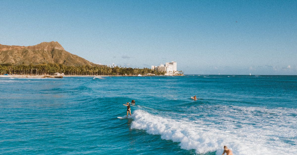 Surfers riding waves at Waikiki Beach with Diamond Head in the background