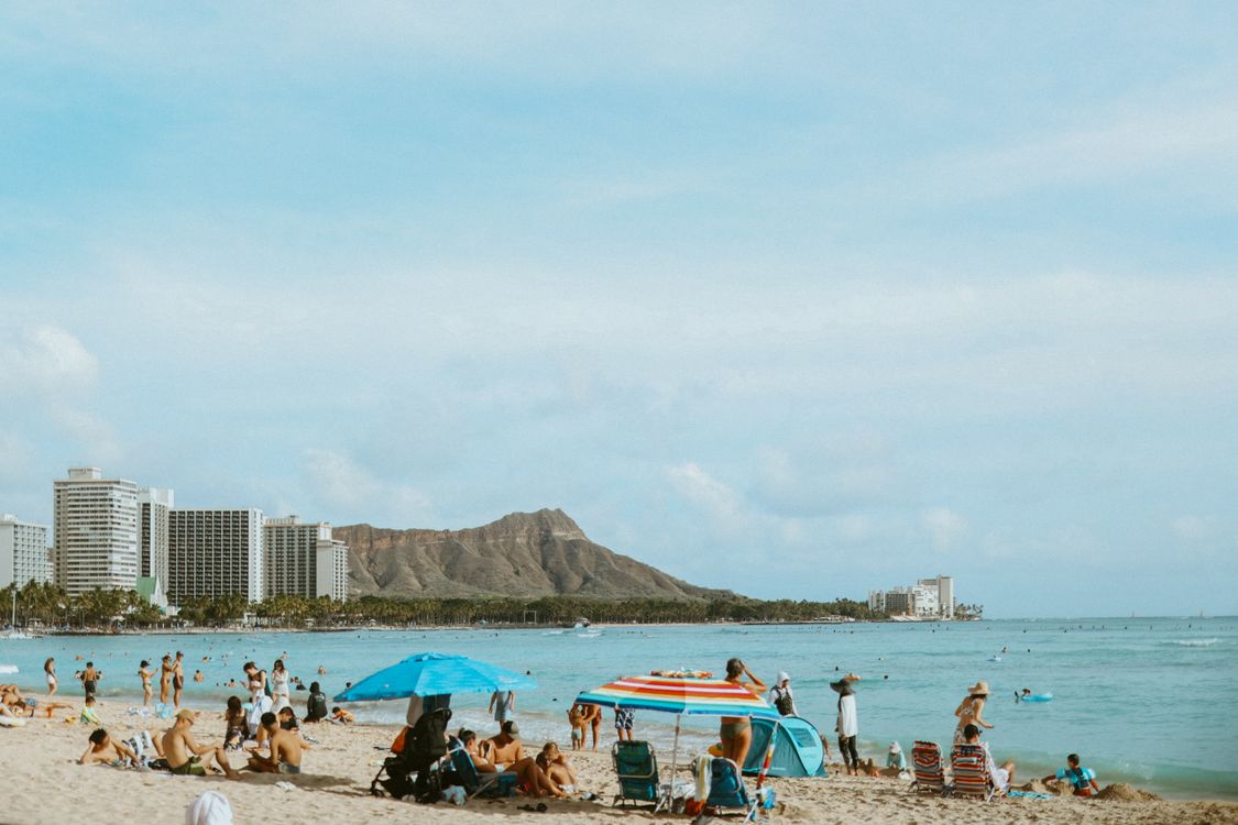 Relaxing Waikiki beach scene with people, umbrellas, and Diamond Head backdrop